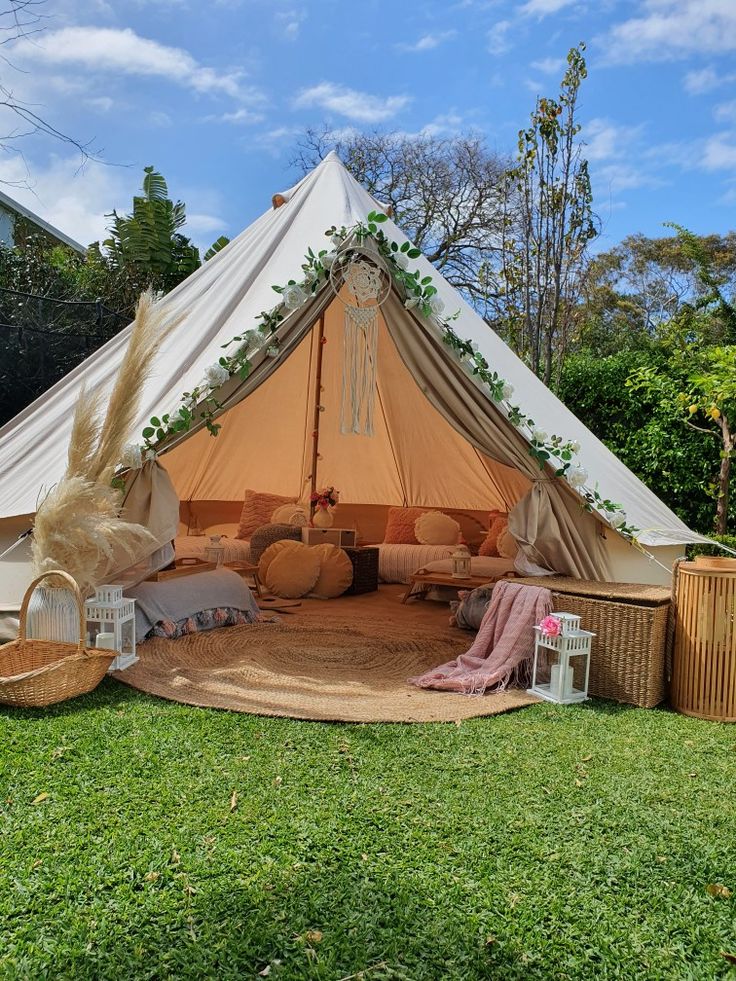 a tent set up in the middle of a yard with furniture and decorations around it