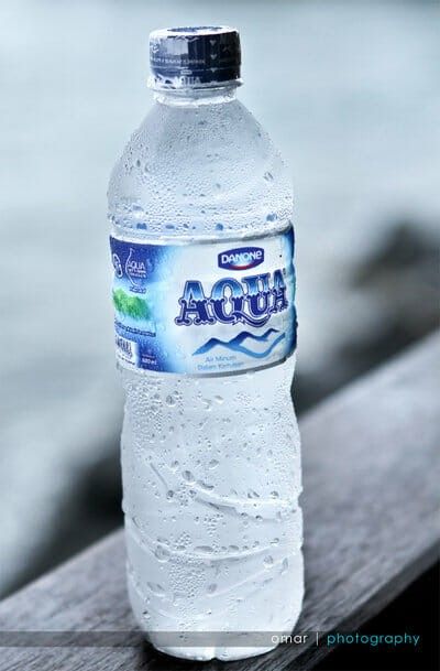 a bottle of water sitting on top of a wooden bench