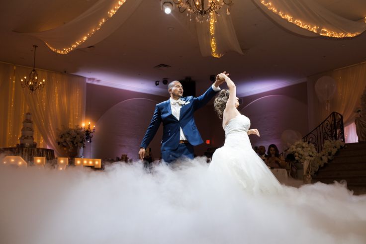 a bride and groom are dancing in the clouds at their wedding reception with chandeliers hanging from the ceiling