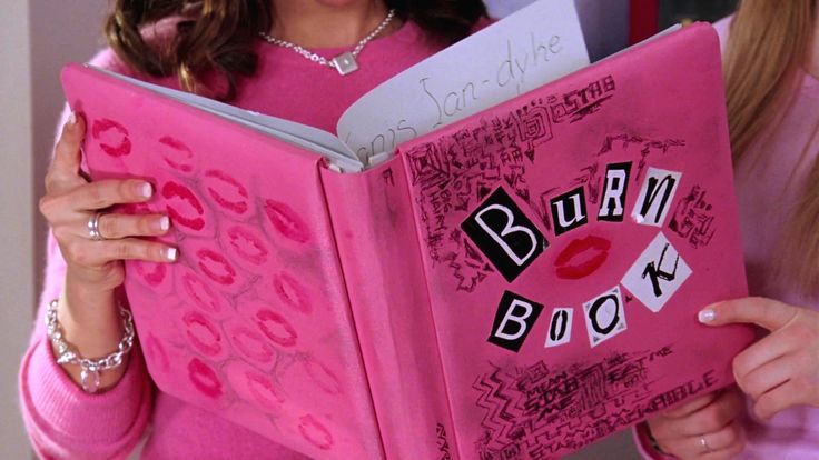 two women in pink shirts are reading a book with the words burn back on it