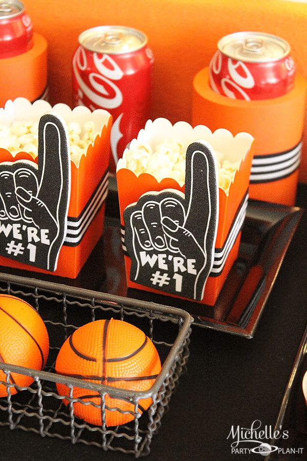 some orange sodas and basketballs are sitting on a tray next to each other