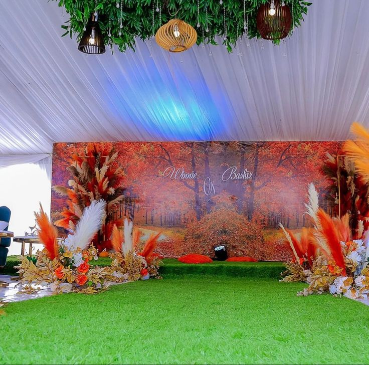 an image of a wedding stage setting with flowers and feathers on the grass in front of it