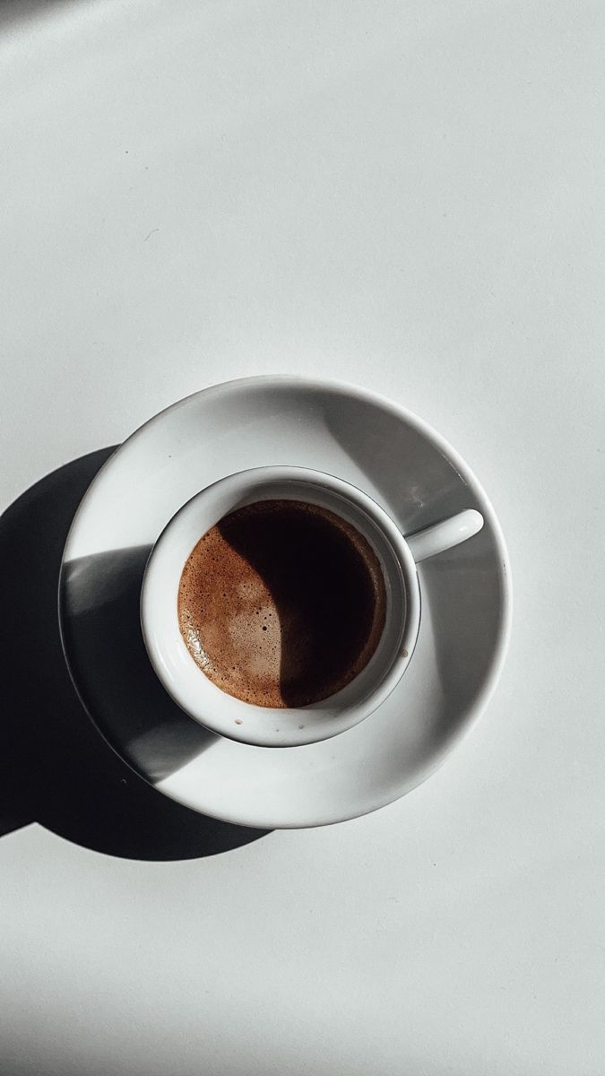 a cup of coffee sitting on top of a white saucer