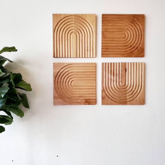 three square wooden plaques mounted on a wall next to a potted plant in a corner