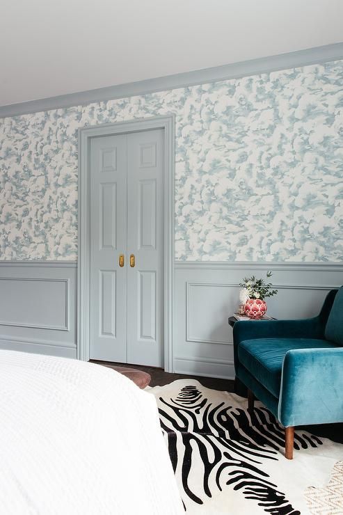 a bedroom with a zebra rug and blue chair in front of the door that leads to another room