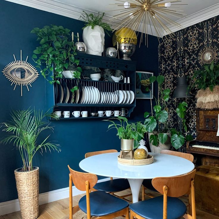 a dining room with blue walls and wooden chairs, potted plants on the wall