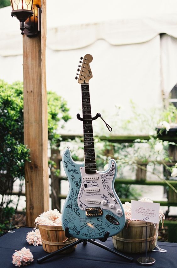 a blue guitar sitting on top of a table next to a basket filled with flowers