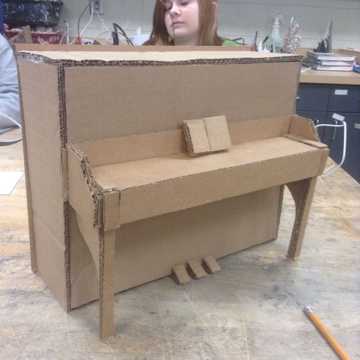 a woman sitting at a desk made out of cardboard