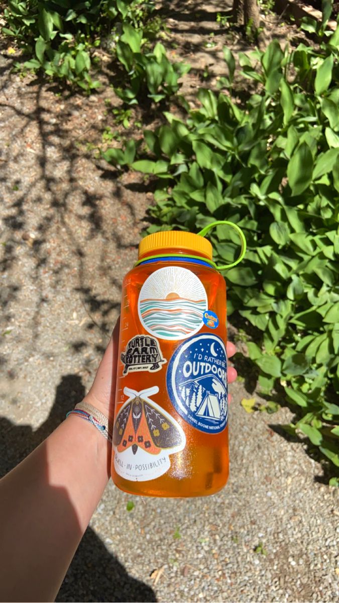 a hand holding a bottle of orange liquid