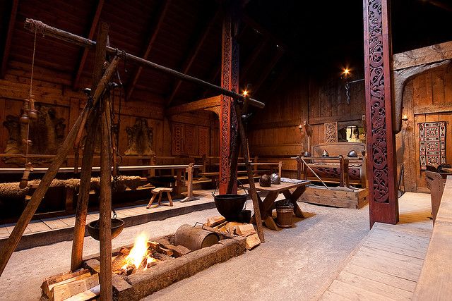 the interior of an old wooden building with logs and fire