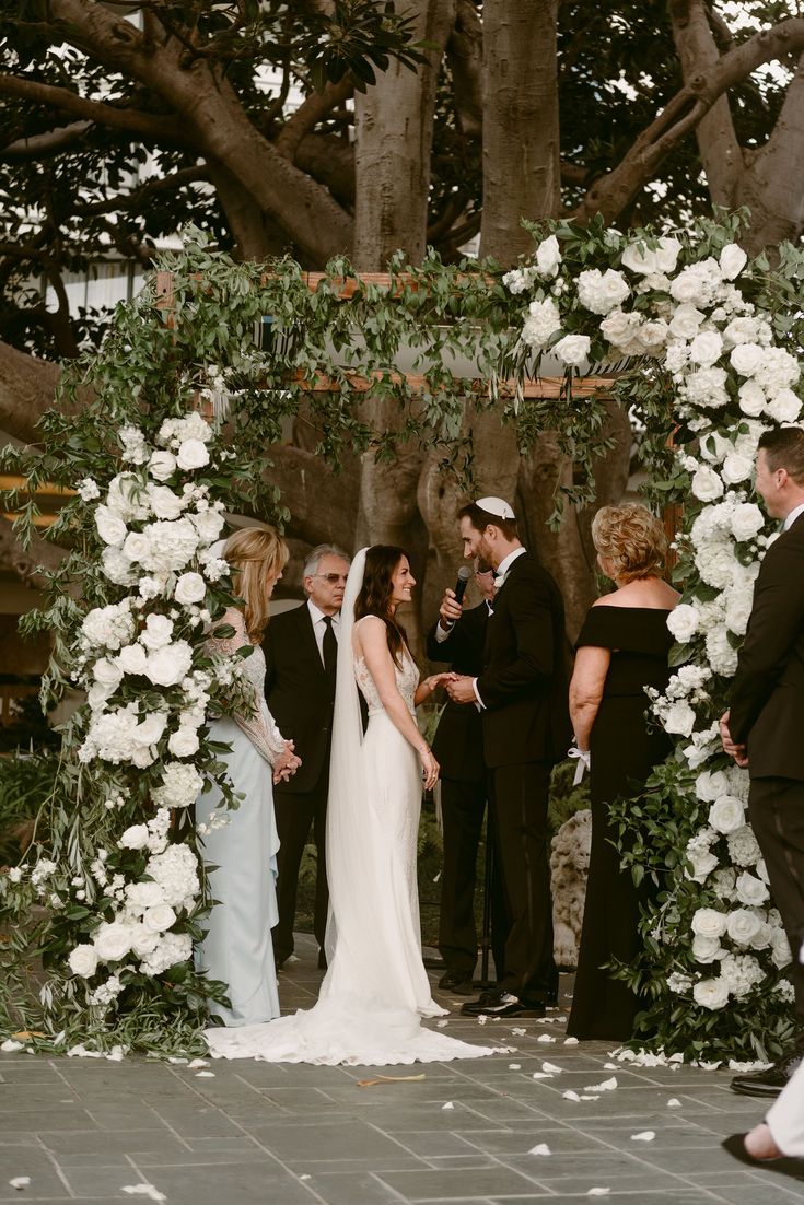 a bride and groom standing at the end of their wedding ceremony under an arch with white flowers