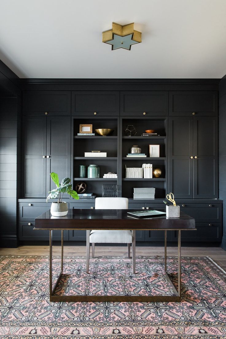 an office with black cabinetry and rug