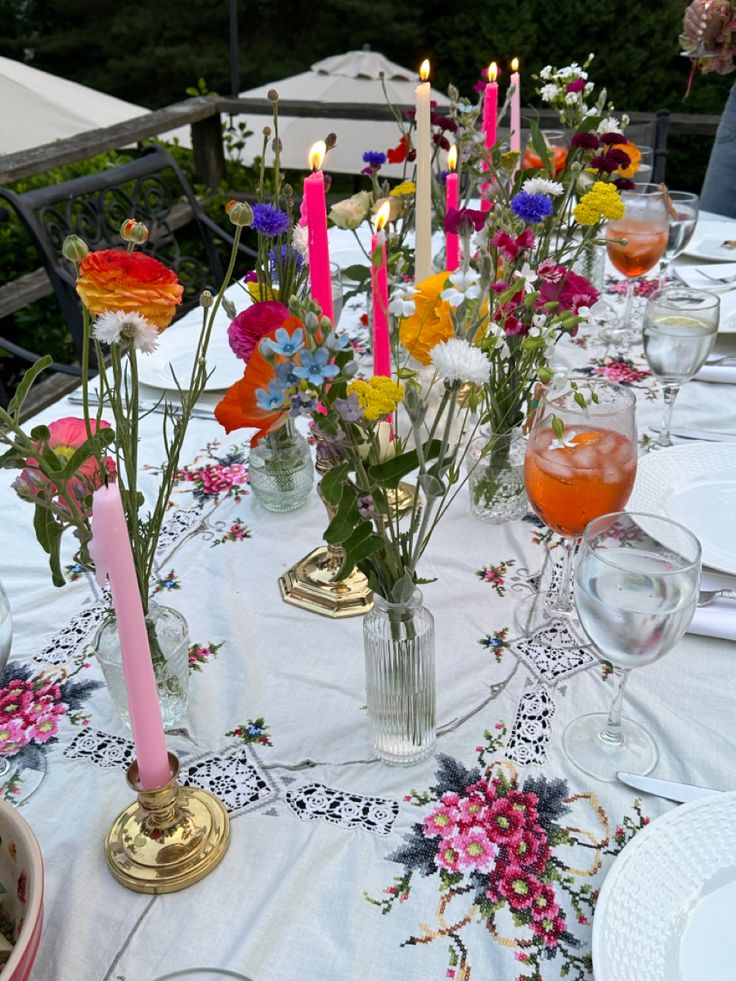 the table is set with flowers and candles on it for an outdoor dinner or brunch