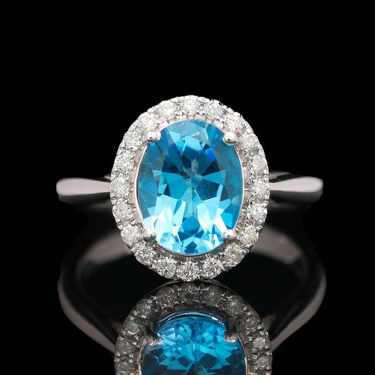 an oval shaped blue topazte and diamond ring in white gold with diamonds surrounding it