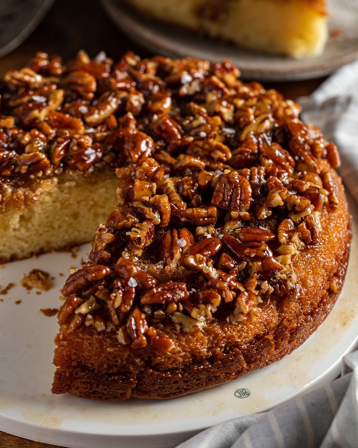 a cake with pecans on top is sitting on a plate next to the rest of the cake