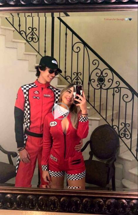 a man and woman dressed in racing outfits taking a selfie with a cell phone