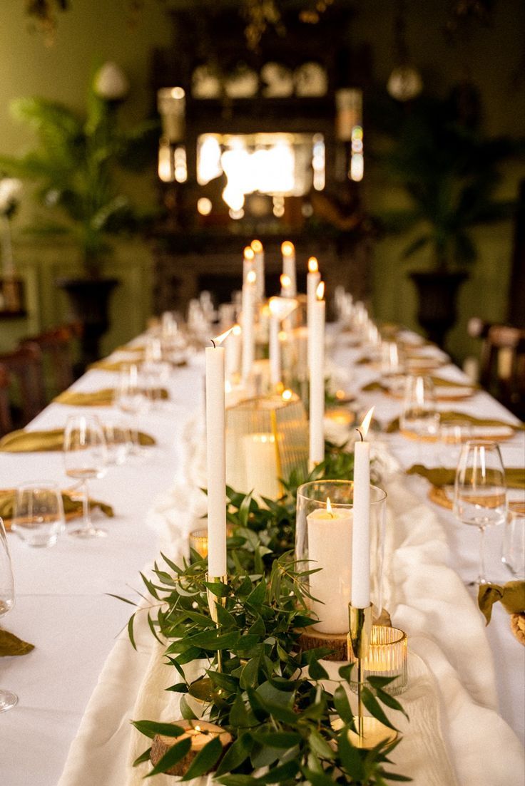 a long table is set with candles and greenery for an elegant dinner or party