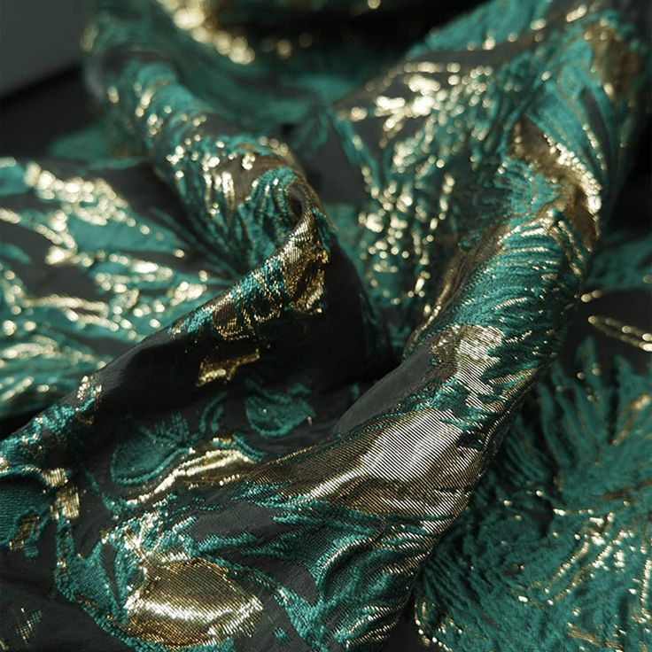 the fabric is shiny and green with gold leaves