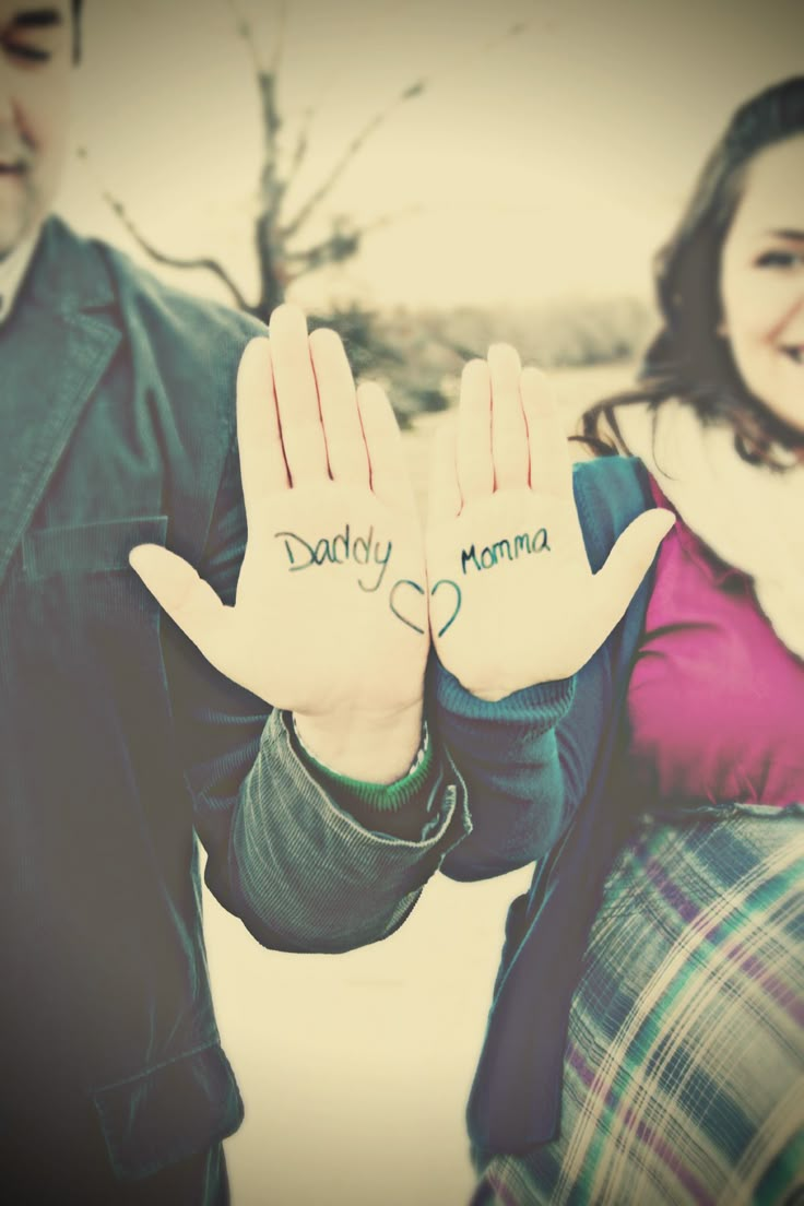 a man and woman holding up their hands with the word daddy written on them