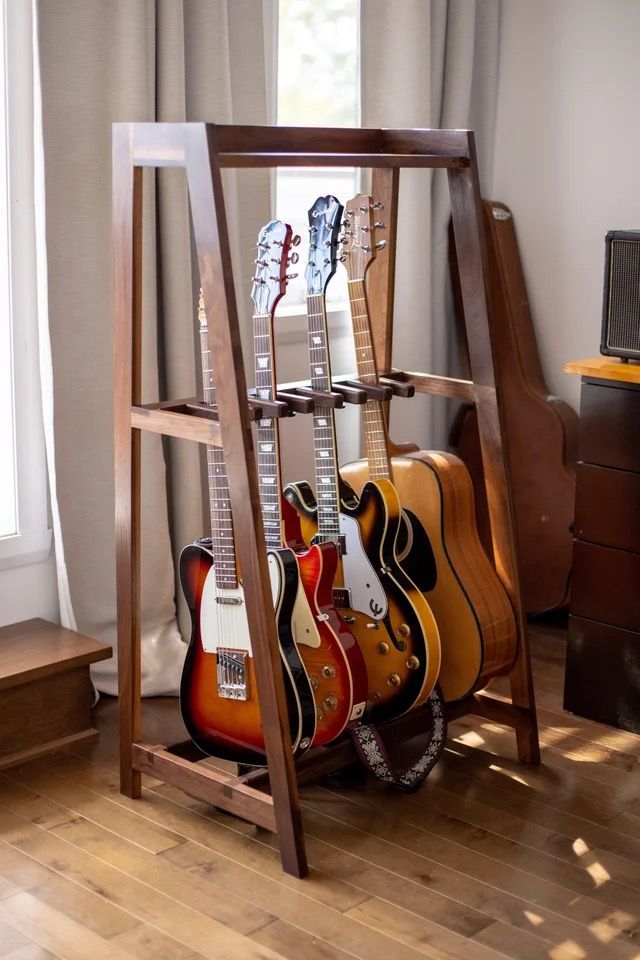 guitars are lined up in a rack on the floor next to a dresser and window