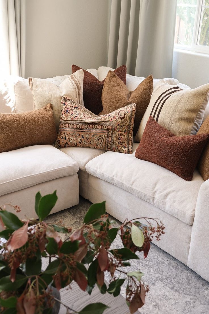 a living room filled with lots of pillows on top of a white couch next to a potted plant