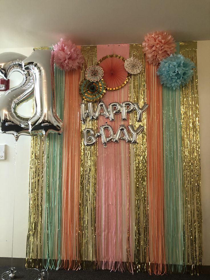 a birthday backdrop with balloons, streamers and flowers on the wall in front of it