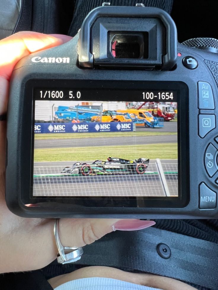 a person is holding up a camera to take a picture of a racing game on the screen