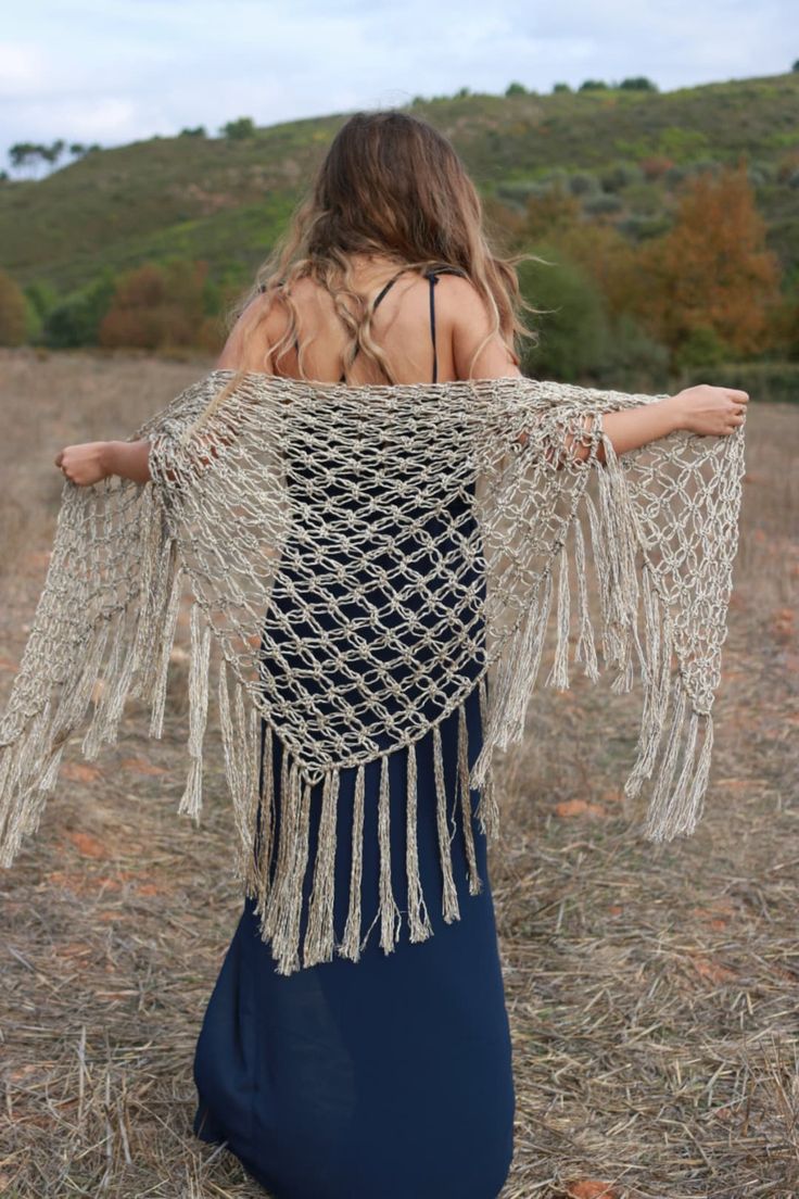 a woman in a blue dress is holding her shawl over her shoulder and looking down at the ground