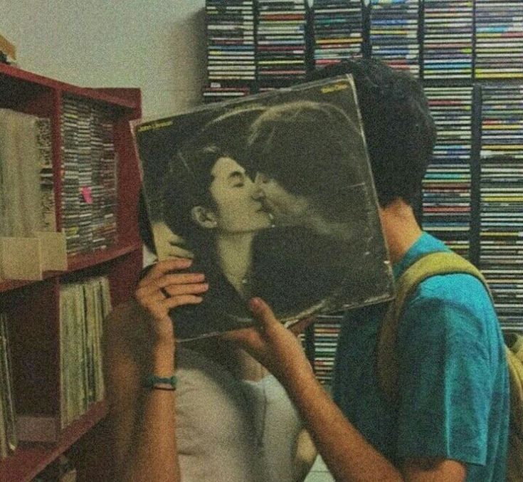 a man holding up a record in front of a woman with her face on the cover