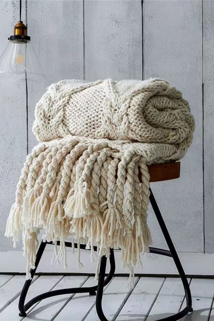 a white blanket sitting on top of a wooden chair