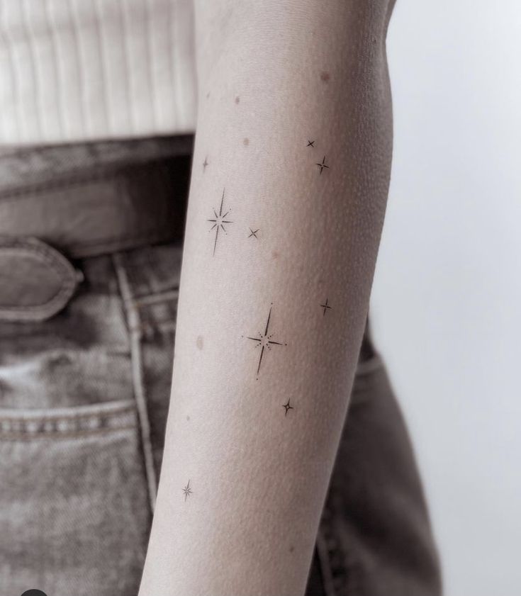 a woman's arm with small stars on the back of her left arm,