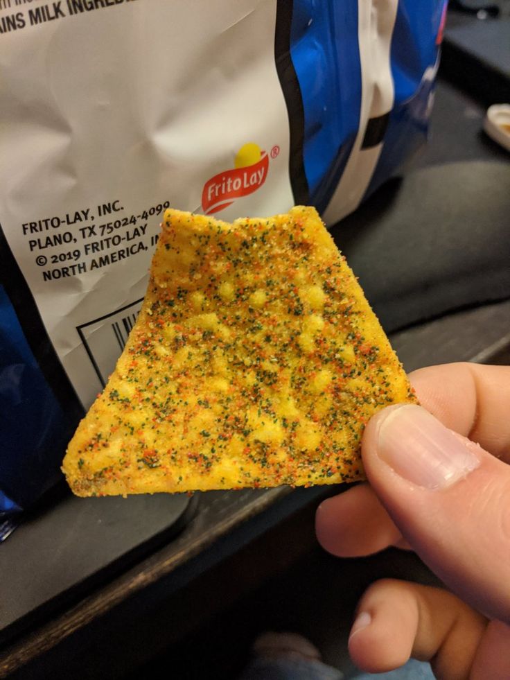 a person holding up a piece of food in front of a bag on the table