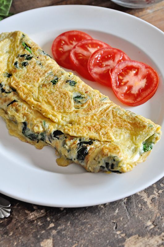 an omelet on a white plate with tomatoes