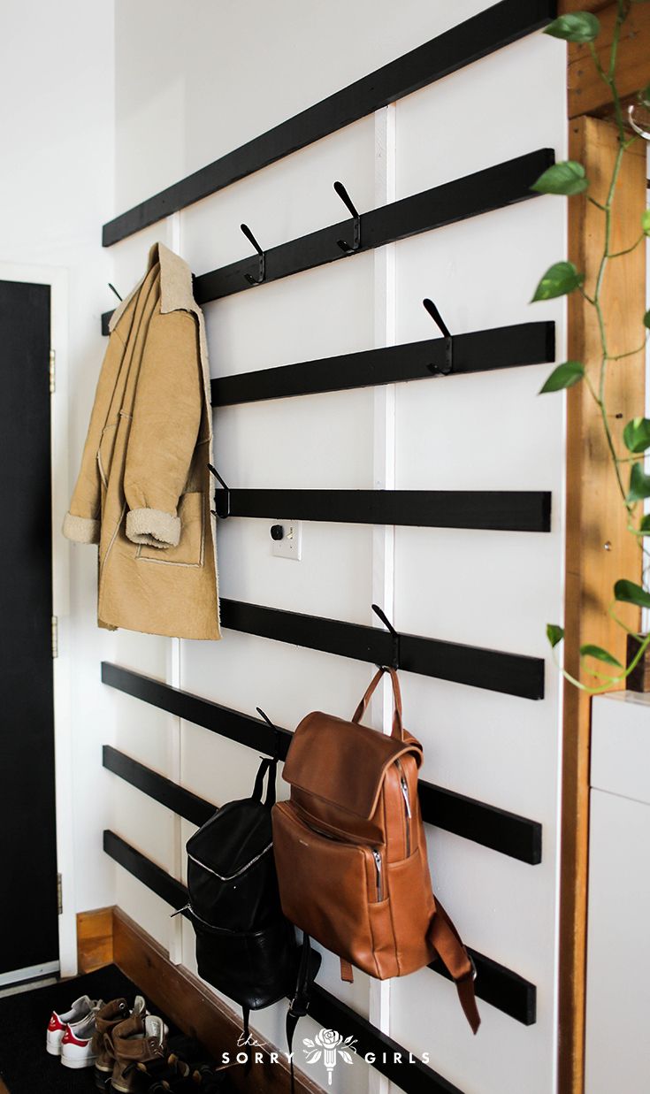 there is a coat rack on the wall next to a backpack and purses in front of it