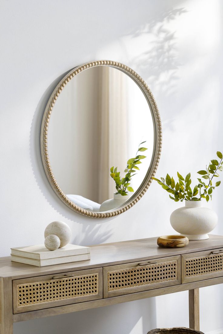 a table with a mirror and vase on top of it next to a plant in a pot