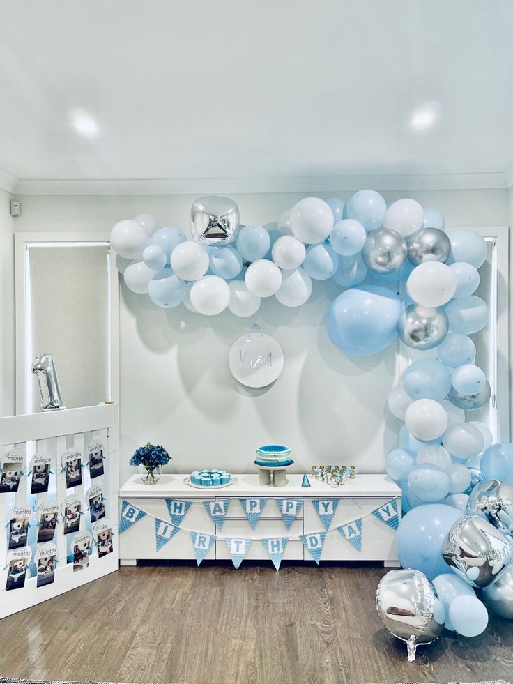 a room filled with balloons and pictures on the wall next to a table covered in blue and white decorations