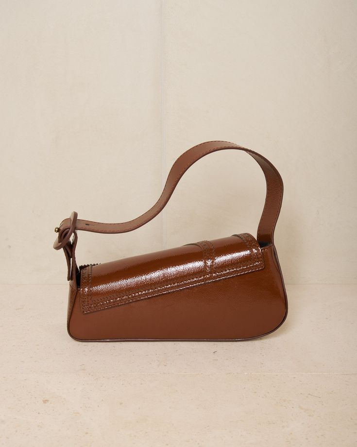 Trivia bag by Kiko Kostadinov in mahogany brown. The signature handbag silhouette from Kiko Kostadinov, presented in deep mahogany calf leather with intricate brogue detailing around the edges. Foldover flap with magnetic closure main compartment. Born in Bulgaria and based in London, Kiko Kostadinov launched his eponymous womenswear line in 2018, delving into an avant-garde aesthetic with innovative fabrics and architectural silhouettes. With Australians Laura and Deanna Fanning at the creative Luxury Brown Baguette Bag For Daily Use, Modern Brown Saddle Bag With Top Handle, Classic Brown Baguette Bag With Top Handle, Luxury Brown Baguette Bag For Everyday Use, Classic Brown Flap Bag With Textured Leather, Classic Brown Textured Leather Flap Bag, Brown Leather Baguette Bag For Office, Brown Top Handle Baguette Bag For Business, Brown Top Handle Saddle Bag With Leather Lining