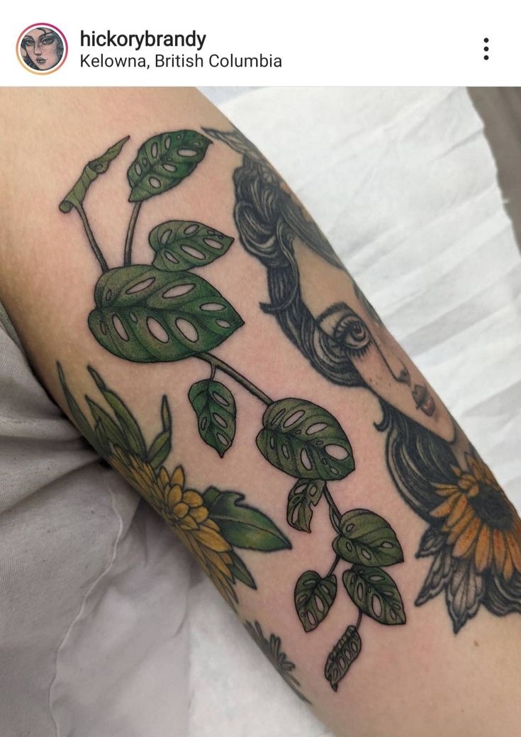 a woman's arm with flowers and leaves on it