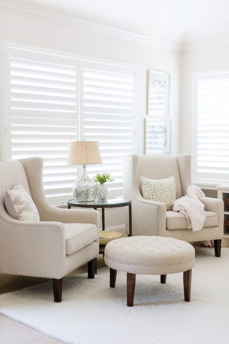 a living room with two chairs and a footstool in front of a window