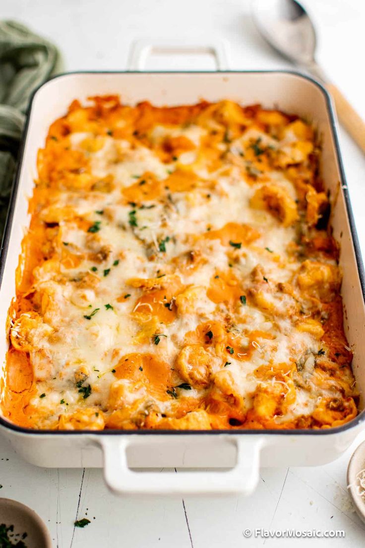 a casserole dish with cheese and spinach in it on a white table