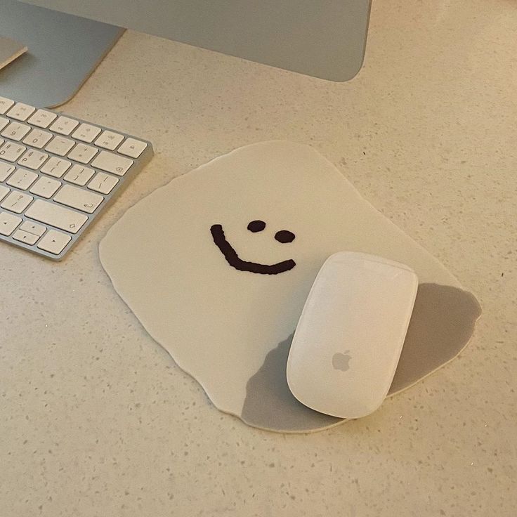 an apple computer with a smiley face on the mouse pad