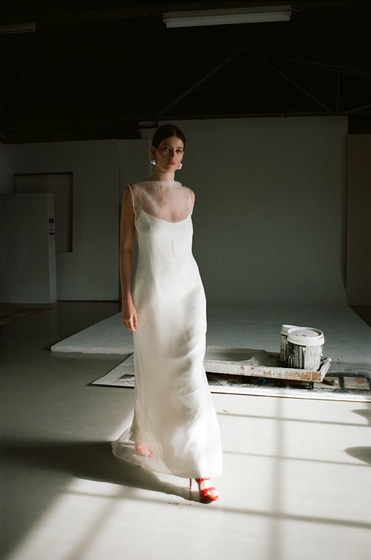 a woman in a white dress is walking down the runway