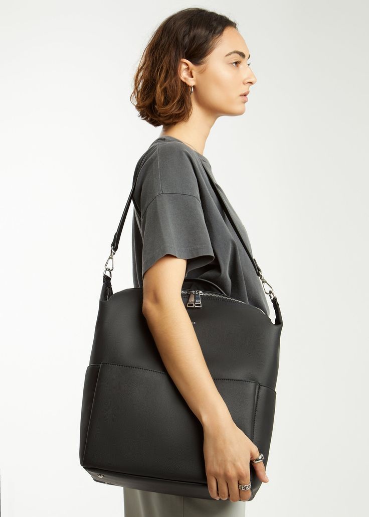 a woman carrying a black leather tote bag