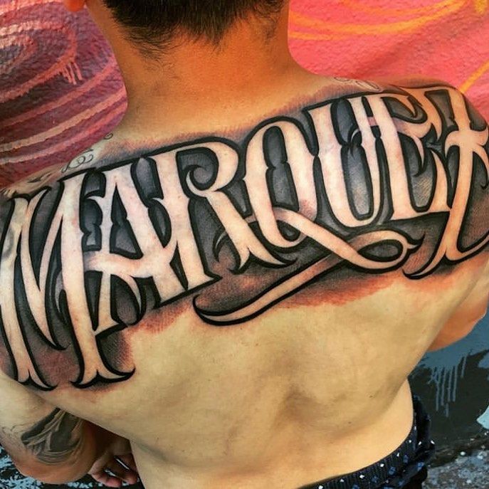 the back of a man's upper half - sleeved tattoo that reads marquat