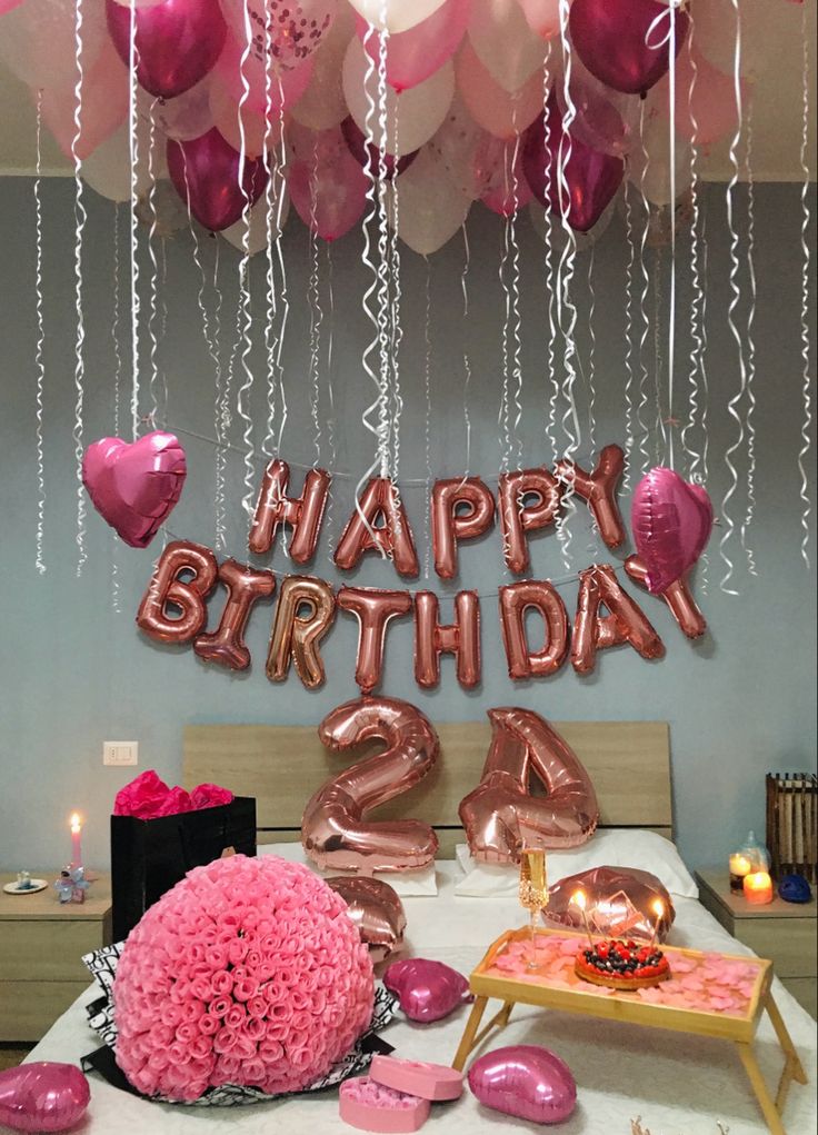 a birthday party with balloons and decorations on the bed in front of it is decorated with pink heart shaped balloons