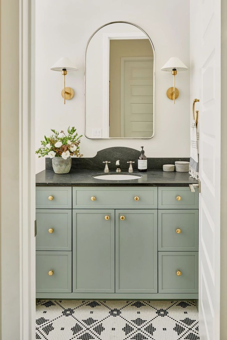 a bathroom with green cabinets and a white sink under a large mirror above the vanity