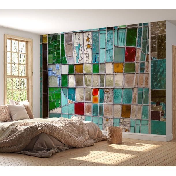 a bed sitting in front of a window covered in lots of colorful glass tiles on the wall