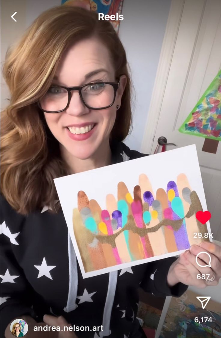 a woman in glasses holding up a card with popsicles painted on it and stars