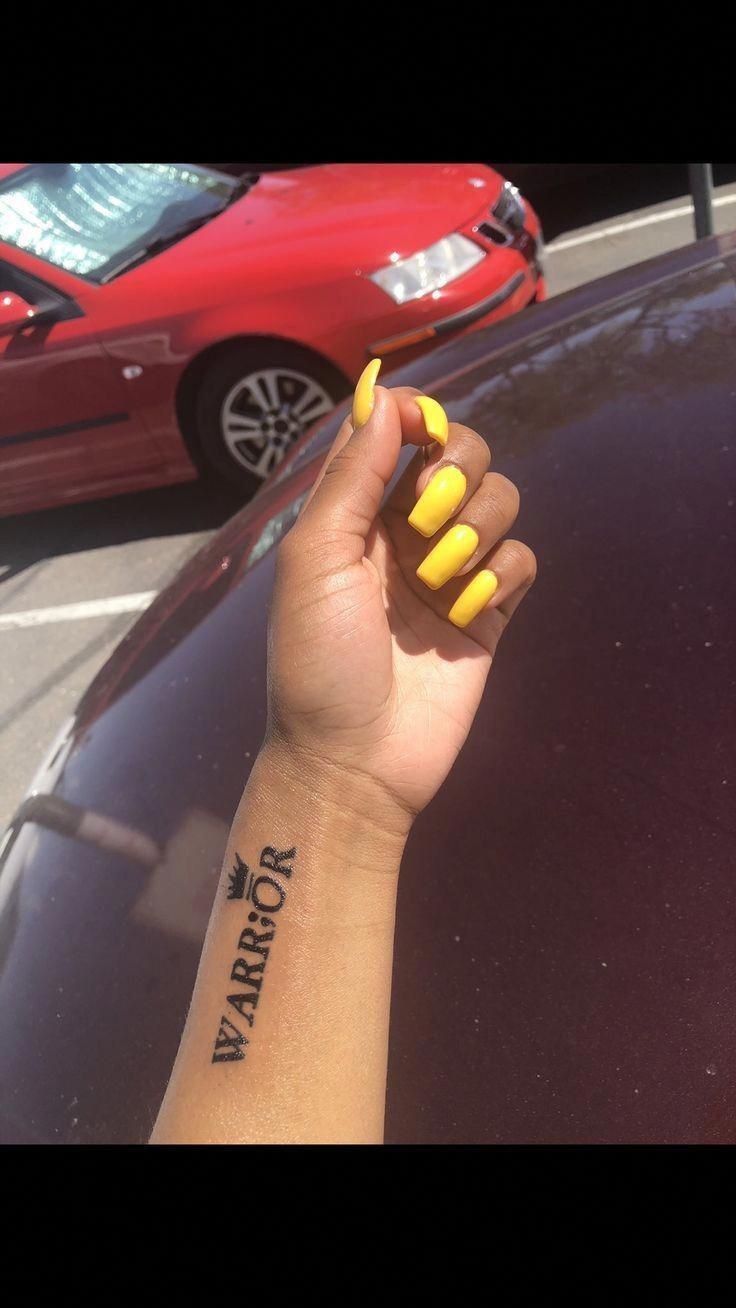 a woman's arm with yellow nail polish on it and a red car in the background