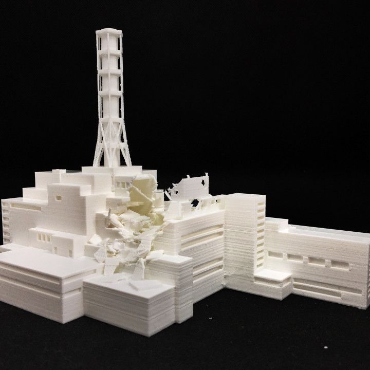 a white model of a building with a tower in the background